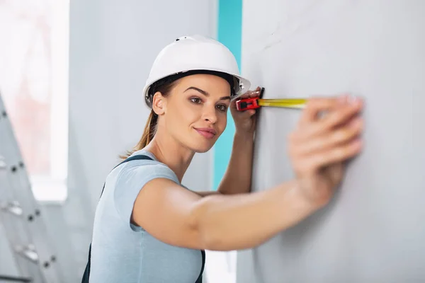 Construtora feminina feliz segurando uma fita métrica — Fotografia de Stock