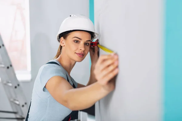 Construtora feminina séria segurando uma fita métrica — Fotografia de Stock
