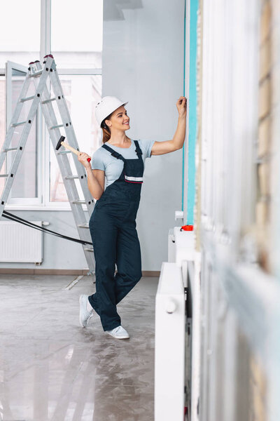 Содержательная женщина-строитель держит молоток
