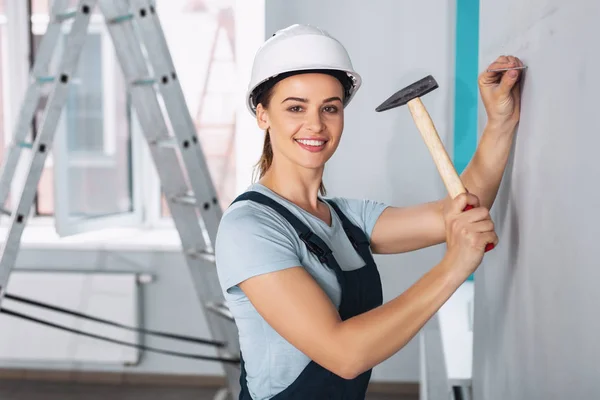 Construtor alegre martelando um prego — Fotografia de Stock