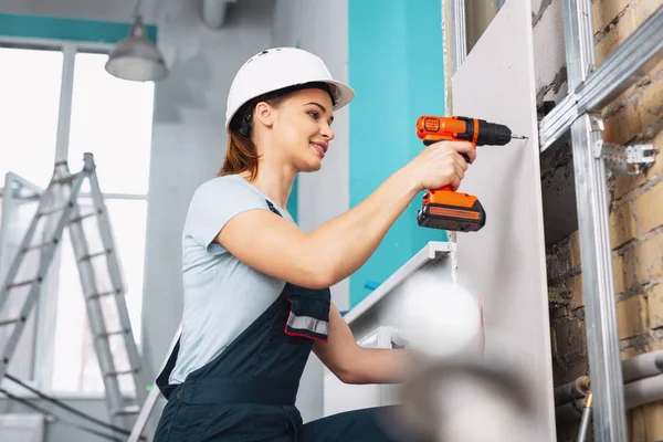 Content female builder working with a drill — Stock Photo, Image