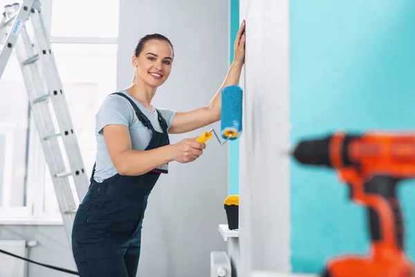 Exuberante constructora femenina sosteniendo un rodillo — Foto de Stock