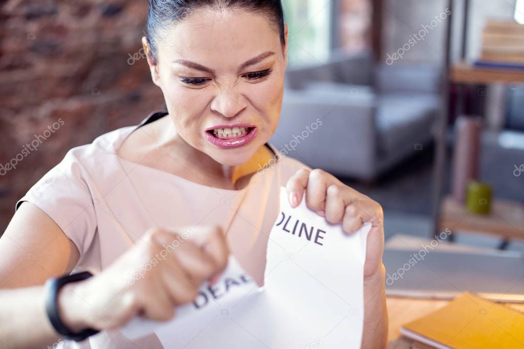 Grumpy female employee ripping apart paper
