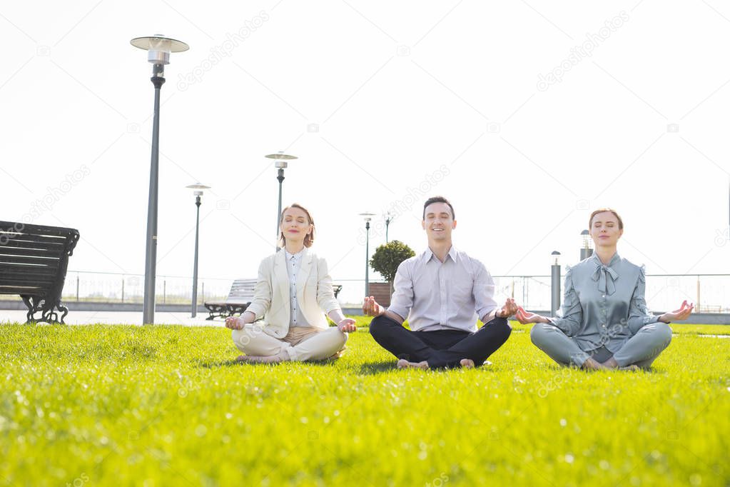 Three stressed corporate leaders feeling relieved while practicing yoga