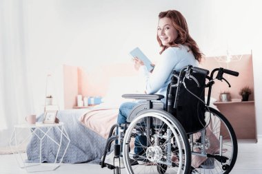 Ona kitap tutan neşeli Engelli Kadın