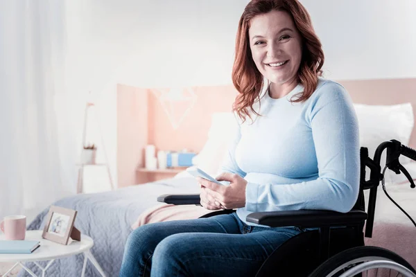 Happy crippled woman holding her phone — Stock Photo, Image