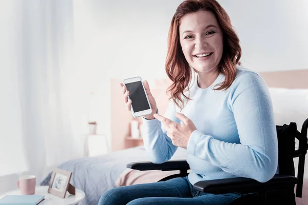 Mujer lisiada alegre sosteniendo su teléfono — Foto de Stock