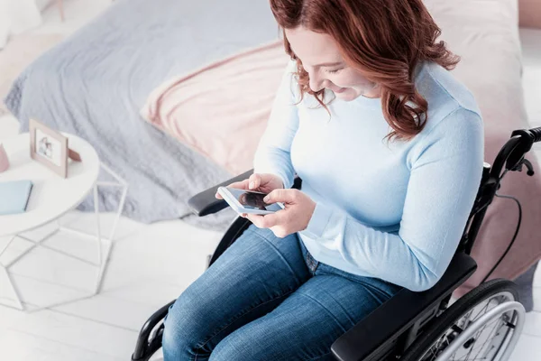 Mujer lisiada alegre sosteniendo su teléfono — Foto de Stock