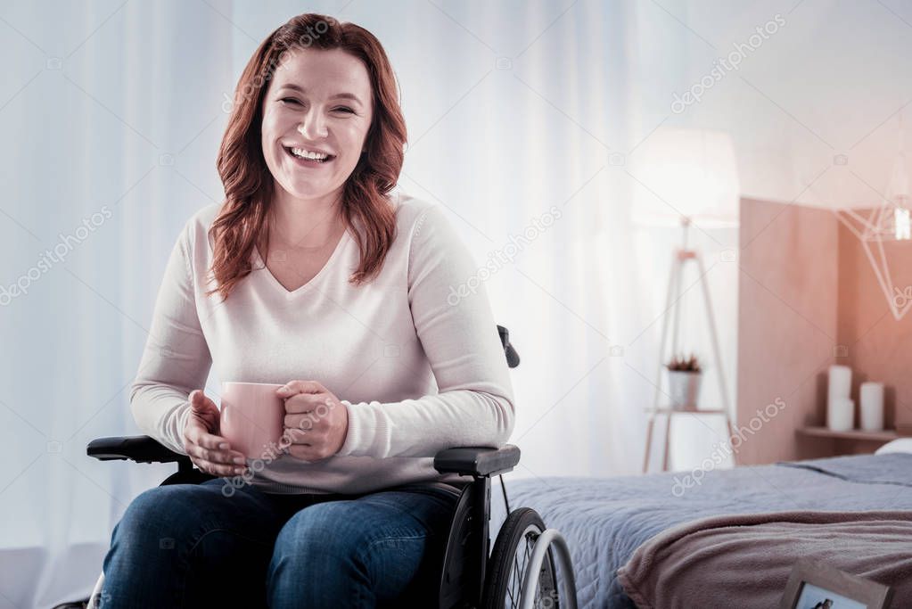 Cheerful disabled woman drinking coffee