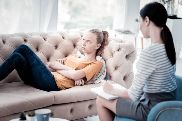 Песимістична дівчина лежить на дивані під час психологічного призначення — стокове фото