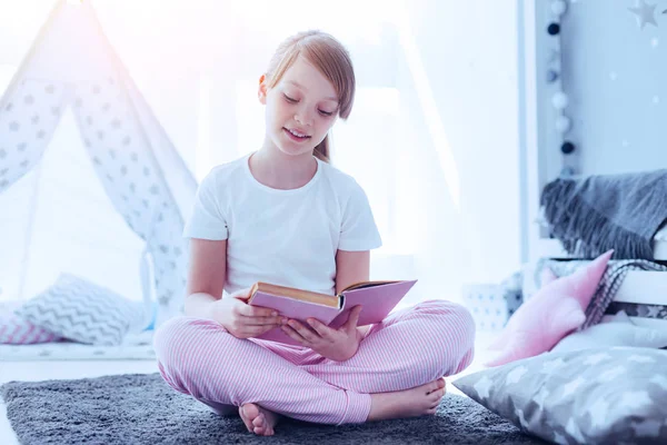 Diligente colegiala disfrutando de nuevo libro en casa — Foto de Stock