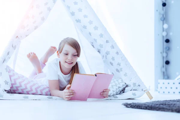 Alegre chica leyendo libro mientras está acostado en el suelo — Foto de Stock