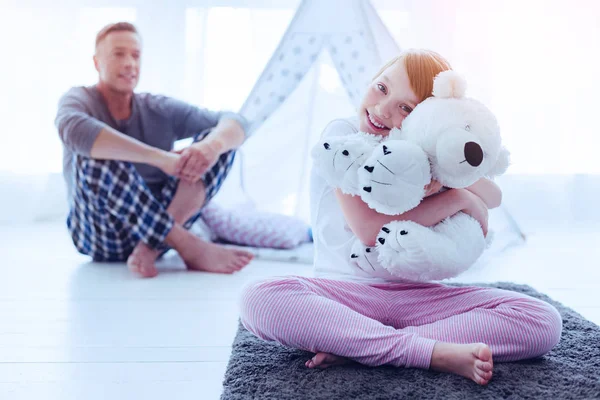 Schattig meisje knuffelen bear speelgoed met vader glimlachend op achtergrond — Stockfoto