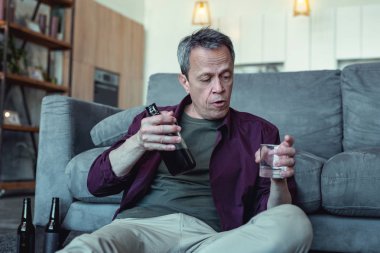 Yüz kırışıklıkları bardak votka ile oturan adam