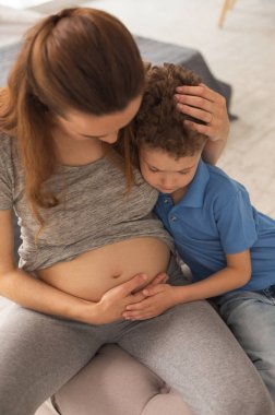 Kıvırcık sevimli çocuk hamile karnıma dokunmaktan meraklı duygu