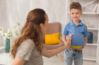 Sevimli kıvırcık çocuk ile hamile anne şaka yaparken eğlenceli duygu