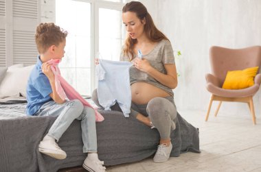 Şefkatli anne ile küçük oğlu gelecekteki İkizler için giysiler seçmek