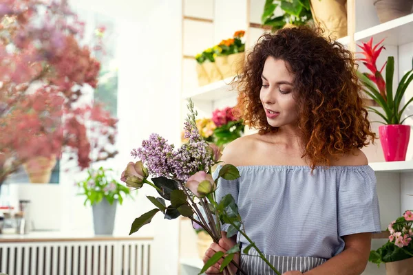 Piacevole donna creativa guardando i fiori — Foto Stock