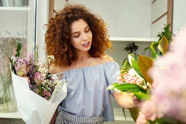Задоволена мила жінка дивиться на квіти — стокове фото