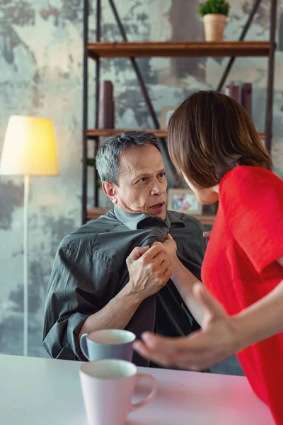 Grey-haired man having dispute with wife in the living room — Stock Photo, Image