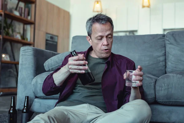 Yüz kırışıklıkları bardak votka ile oturan adam