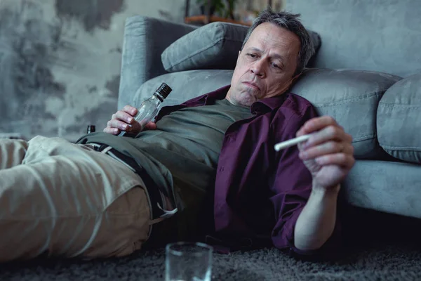 Ubriaco uomo esausto fumare sdraiato sul pavimento — Foto Stock