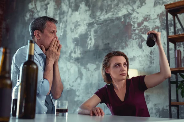 Drunk wife with blue eye sitting near sober disturbed man — Stock Photo, Image