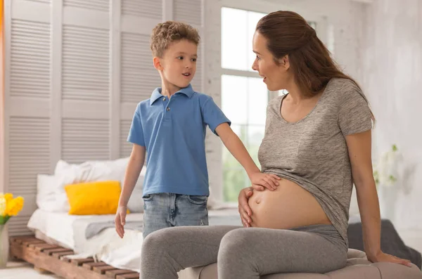 Süßer entzückender Sohn, der seinen Schwangerschaftsbauch berührt — Stockfoto