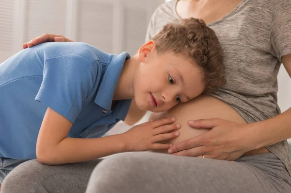 Cuidando hijo amoroso escuchando a su futura hermanita — Foto de Stock