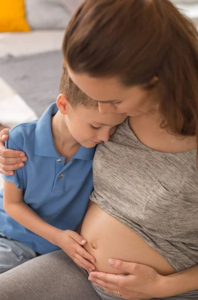 Süßer kleiner Junge umarmt seine schwangere Mutter — Stockfoto