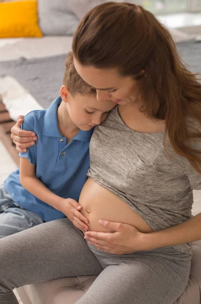 Заботливая беременная мать обнимает своего маленького милого сына — стоковое фото