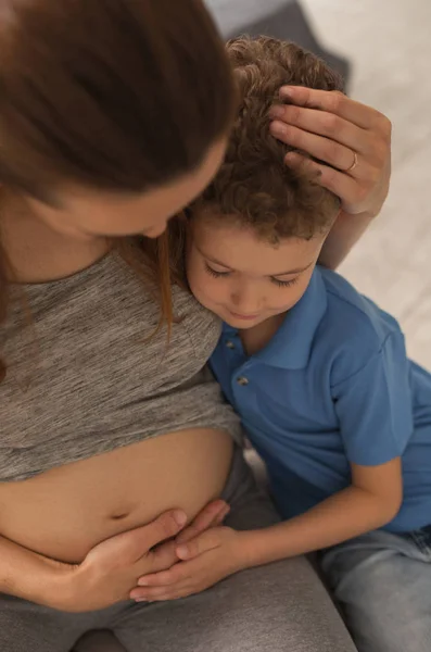 Gravid kvinna bär grå sport passar krama lille son — Stockfoto