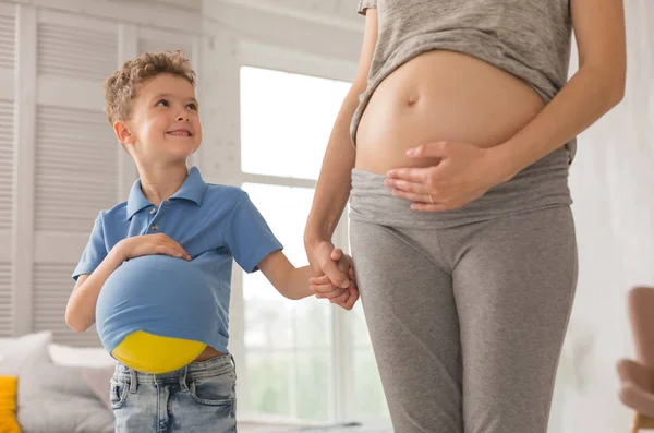 Glücklicher kleiner Sohn blickt seine erwartungsvolle Mutter an — Stockfoto