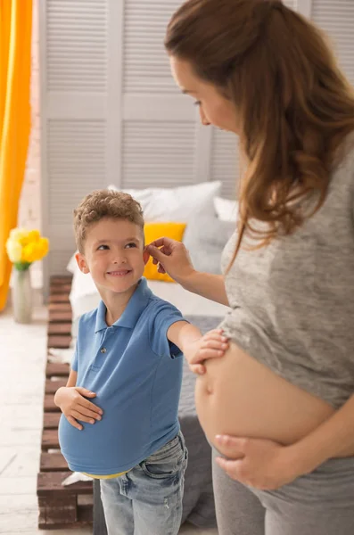 Gravid kvinna med vågigt hår att ta hand om hennes lilla son — Stockfoto