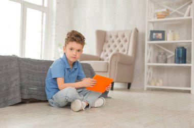 Katta oturan mavi gözlü yakışıklı küçük çocuk