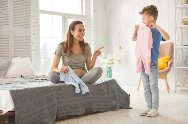 Lockiger kleiner Junge in weißen Turnschuhen kommt zu seiner schwangeren Mutter — Stockfoto