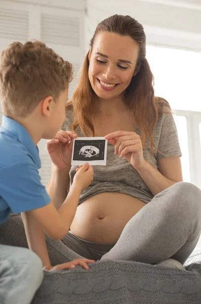 Strahlende attraktive Frau im Gespräch mit Sohn über Geburt — Stockfoto