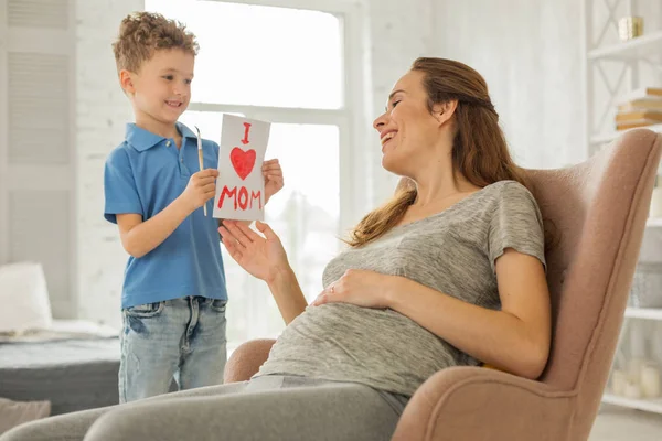 Fürsorglicher Sohn malt Bild für seine schwangere Mutter — Stockfoto