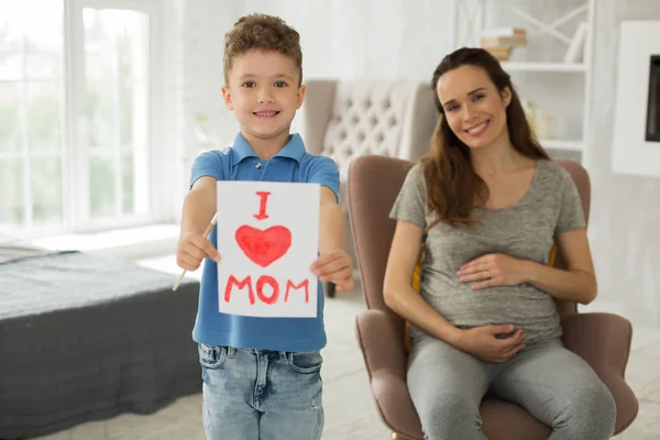 Netter kleiner Junge erzählt seiner schwangeren Mutter von seiner Liebe — Stockfoto
