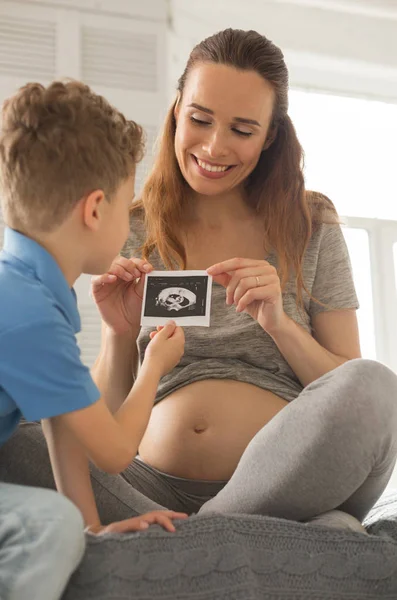 Beaming appealing woman talking with son about chilbirth — Stock Image Beaming appealing woman talking with son about chilbirth Stock Picture