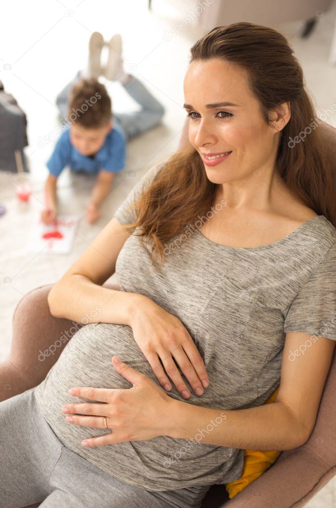 Dark-haired appealing pregnant woman feeling thoughtful