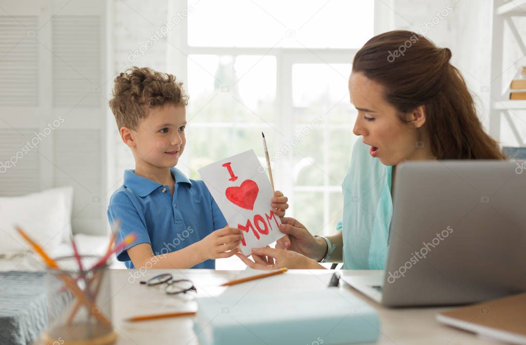 Mother feeling pleasantly surprised looking at cute picture