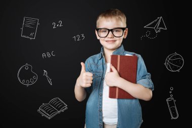 Sevgi dolu okul. Bir defter tutan ve okula gitmekten tadını çıkarırken parmağını koyarak neşeli çalışkan öğrenci