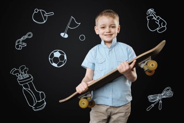 Gülümseyen ve yeni bir hızlı kaykay tutan mutlu çocuk