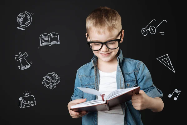 Улыбающийся школьник в очках во время чтения — стоковое фото