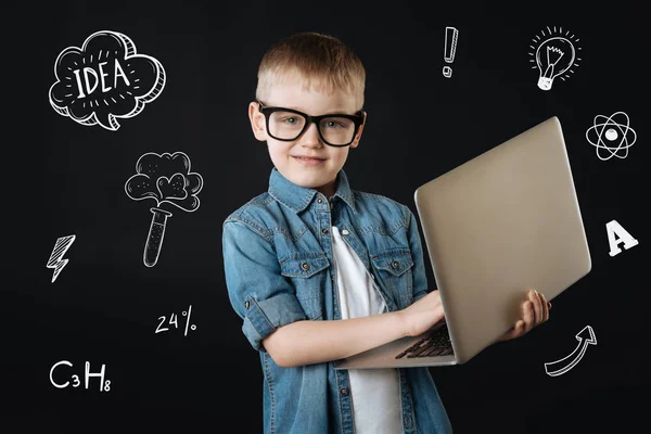 Прогрессивный ребенок чувствует себя уверенно, держа в руках современный ноутбук — стоковое фото