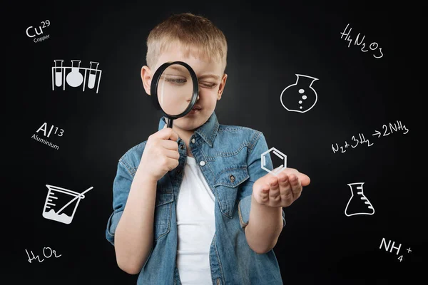 Nieuwsgierig jongen houdt een vergrootglas en op zoek doorheen — Stockfoto