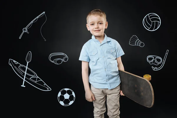 Glücklicher Junge, der sich im Stehen mit einem neuen Skateboard sicher fühlt — Stockfoto