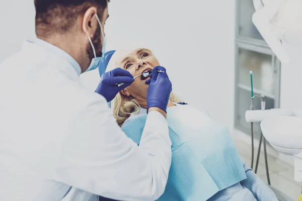 Tiivistetty stomatologist tutkii hänen vierailija — kuvapankkivalokuva