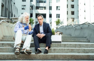 İki buruşuk adam ofis binası dışında bira içmek